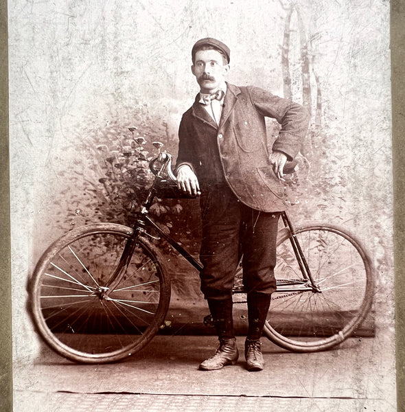 Studio portrait of a man leaning against his bicycle, 1897