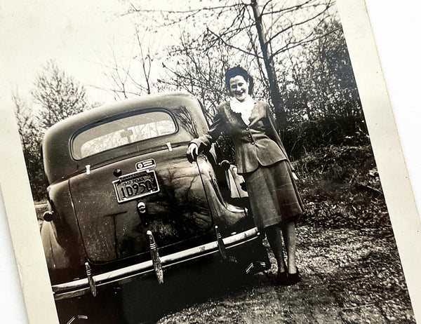 1942 snapshot of a woman posed next to a National Defense automobile