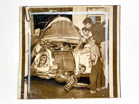 Press photograph of two men and a boy inspecting a wrecked car (with publication markups)