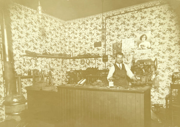 Photograph of a cobbler at the repair counter, ca. 1930s