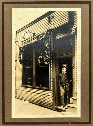 Exterior photograph of a young man in the doorway of Al's Shoe Repair & Shoe Shine Parlor