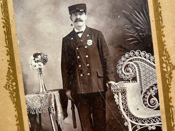 Cabinet photo of a U.S. Marshall with a Wyatt Earp mustache, billy club, cap, and badge...
