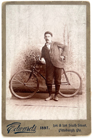 Studio portrait of a man leaning against his bicycle, 1897
